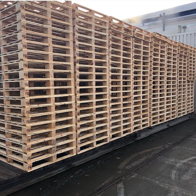 Wooden pallets stacked on a trailer outside a building