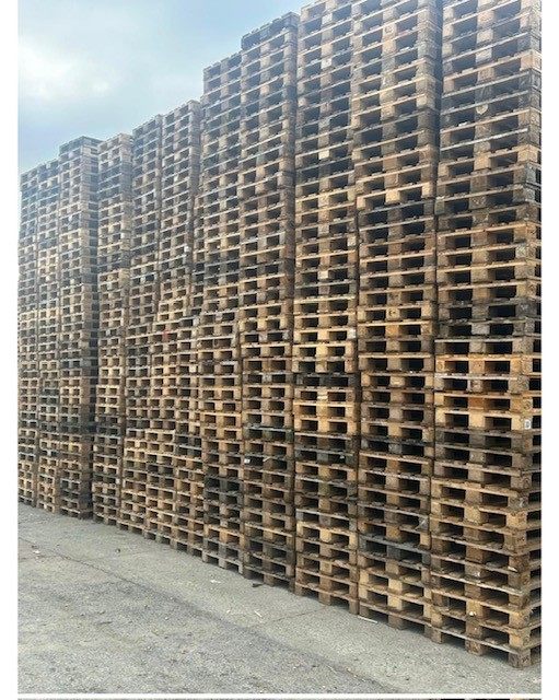 Tall stacks of weathered wooden pallets